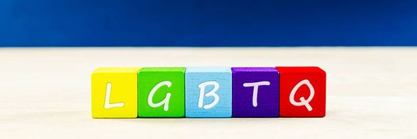 レズビアン、ゲイ、バイセクシャル、トランスジェンダー、クィアのコミュニティのための概念的なイメージで虹色の木製のブロックにLGBTQのサイン. - 写真・画像