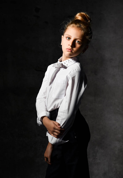 Little female caucasian model posing in school uniform on a gray concrete studio background. - Fotoğraf, Görsel