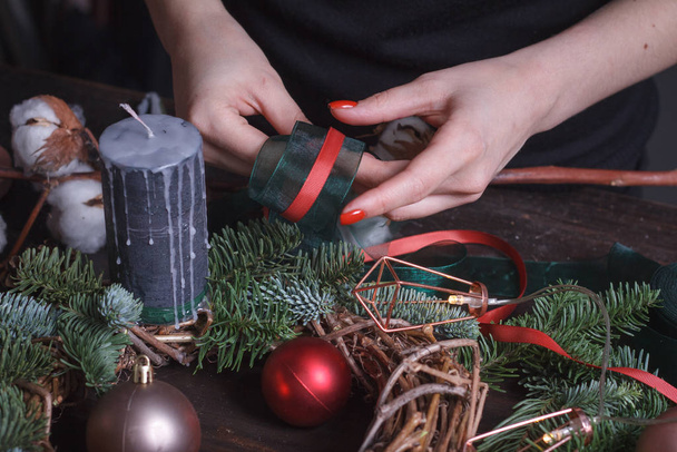 Nahaufnahme einer Floristin, die einen Weihnachtskranz aus Tannenzweigen, Weihnachtsblasen und natürlichem Dekor herstellt, selektiver Fokus - Foto, Bild