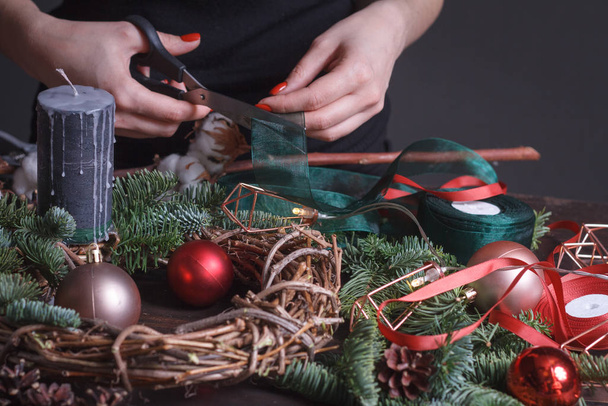 Крупним планом жіночий флорист робить різдвяний вінок з ялинкових гілок, різдвяних бульбашок і природного декору, вибірковий фокус
 - Фото, зображення