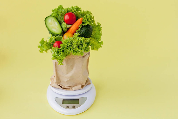 Fresh vegetables on scales on yellow background. Vegan and healt - Фото, изображение