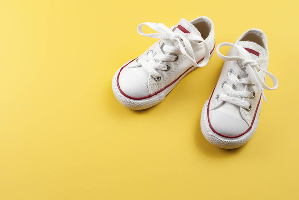Photo of white sneakers over yellow background. - Foto, afbeelding