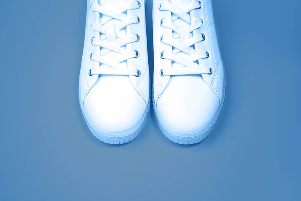 White sneakers are lying on a blue color background. - Fotografie, Obrázek