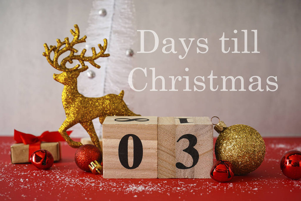 3 dias antes do Natal, um calendário de madeira com um veado de ouro e decorações em um fundo de madeira vermelho-cinza. Um dos 3 dias da série
. - Foto, Imagem