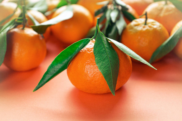 Orange tangerines with leaves on an orange background. - Foto, imagen