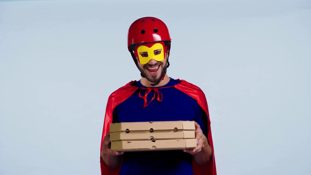 smiling superhero holding boxes with pizza isolated on blue  - Πλάνα, βίντεο