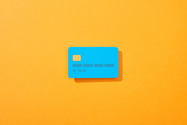 top view of blue credit card template on orange background - Foto, Imagen