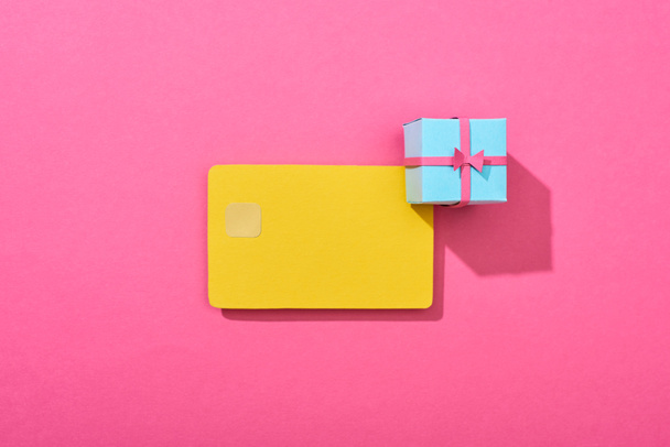 top view of yellow empty credit card with gift box on pink background - Photo, Image