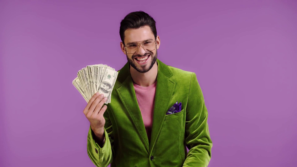 man in velour jacket pointing with finger at money isolated on purple - Footage, Video