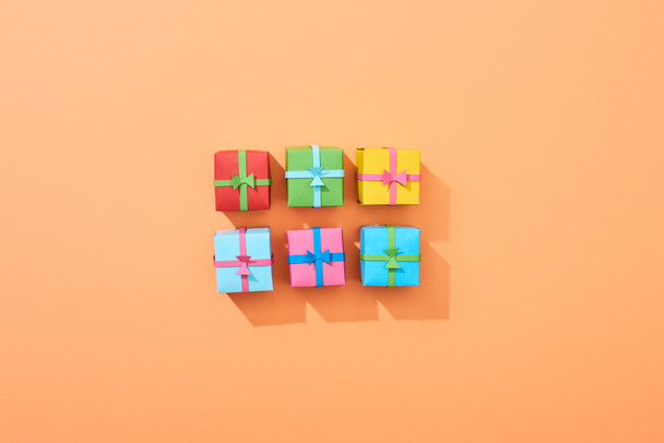 vista superior de pequeñas cajas de regalo multicolores sobre fondo melocotón
 - Foto, Imagen