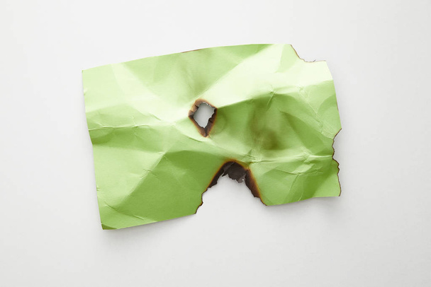 top view of empty crumpled and burnt green paper on white background - 写真・画像