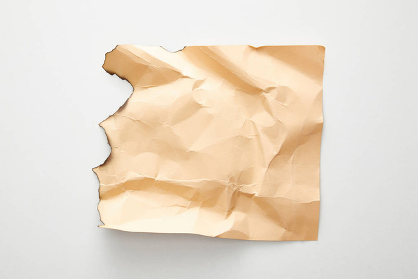 top view of empty crumpled and burnt beige vintage paper on white background - Foto, Imagem