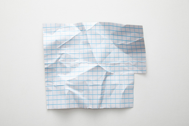 horní pohled na prázdný zmačkaný mřížkový papír na bílém pozadí - Fotografie, Obrázek