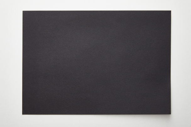 Draufsicht auf leeres schwarzes Papier auf weißem Hintergrund - Foto, Bild
