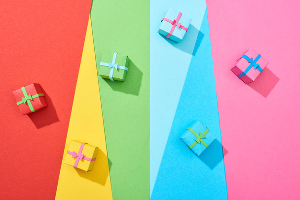 top view of multicolored gift boxes scattered on rainbow background - 写真・画像