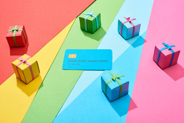 tarjeta de crédito vacía y cajas de regalo multicolores sobre fondo de arco iris
 - Foto, imagen