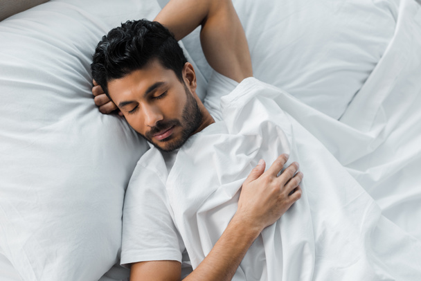 vrchol pohled na pohledný bi-rasový muž spí v posteli v dopoledních hodinách  - Fotografie, Obrázek