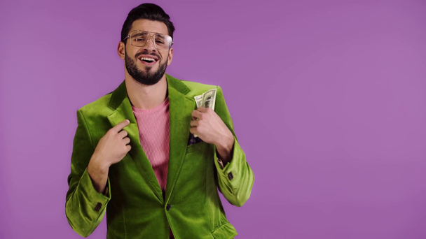 muž v sametové bundě házet peníze izolované na fialové - Záběry, video