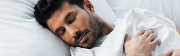 plano panorámico de hombre bi-racial guapo durmiendo en la cama en la mañana
  - Foto, Imagen