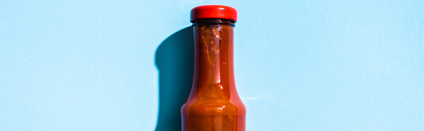 Верхний вид бутылки с кетчупом на голубом фоне, панорамный снимок
 - Фото, изображение