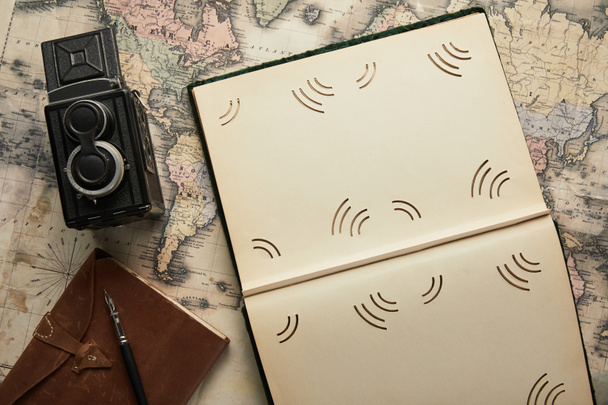 top view of vintage camera, notepad with fountain pen, empty photo album on map background - Photo, Image