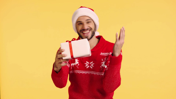 sonriente hombre sosteniendo caja de regalo aislado en amarillo
 - Imágenes, Vídeo