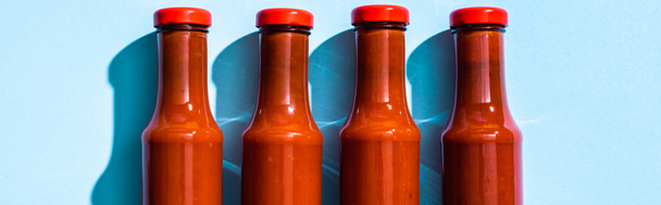 Vista superior de botellas con salsa de tomate sobre fondo azul, plano panorámico
 - Foto, imagen