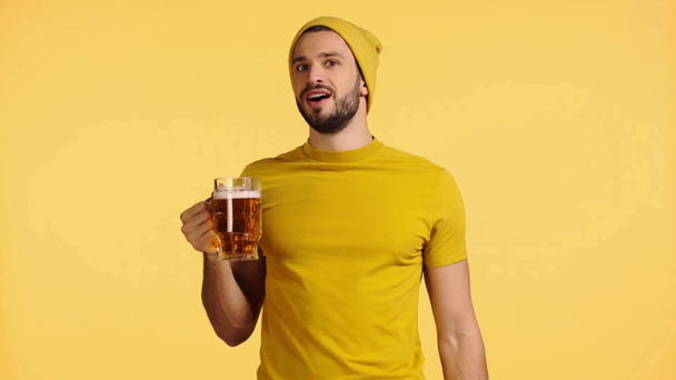 mosolygós férfi ivás sör izolált sárga - Felvétel, videó