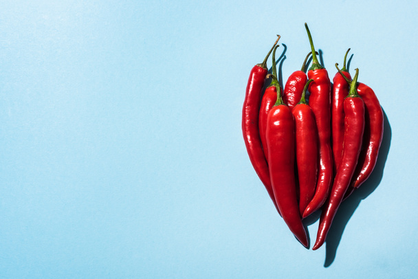 Top view of fresh organic chili peppers on blue background - Valokuva, kuva