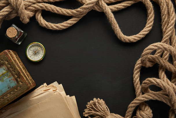 top view of vintage paper, rope, compass and painting on black background - Φωτογραφία, εικόνα