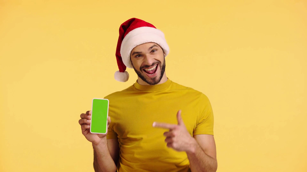 hombre apuntando con el dedo al teléfono inteligente aislado en amarillo
 - Imágenes, Vídeo