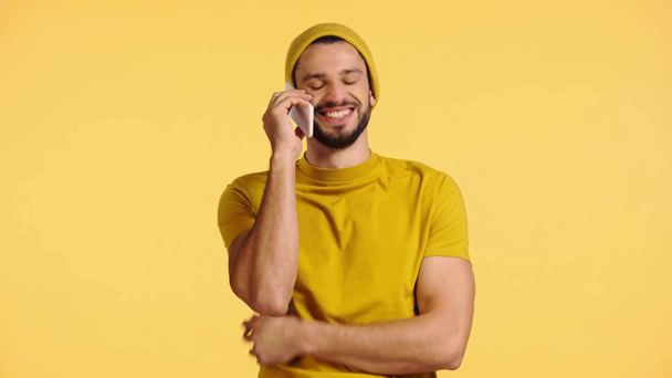 sonriente hombre hablando en teléfono inteligente aislado en amarillo
 - Imágenes, Vídeo