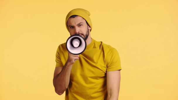 angry man shouting in megaphone isolated on yellow - Footage, Video