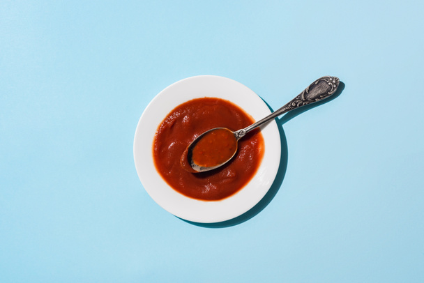 Top view of plate of delicious tomato sauce on blue surface - Photo, Image