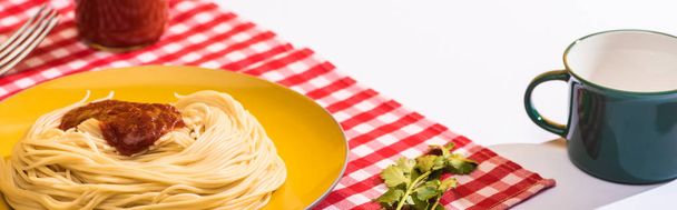 Deliciosos espaguetis con ketchup al lado de la taza sobre fondo blanco, plano panorámico
 - Foto, Imagen