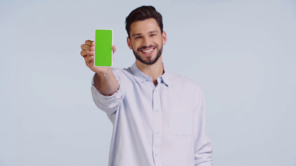 улыбающийся мужчина, указывающий пальцем на смартфон, изолированный на голубом
  - Кадры, видео