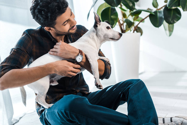 smiling and handsome bi-racial man holding Jack Russell Terrier - 写真・画像