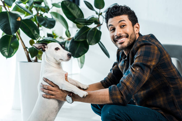 handsome and smiling bi-racial man holding jack russell terrier - Photo, image