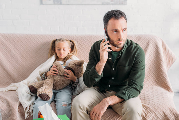 poważny człowiek mówi na smartfonie siedząc blisko chory córka - Zdjęcie, obraz