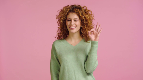 glimlachende vrouw tonen ok gebaar en knikken geïsoleerd op roze - Video