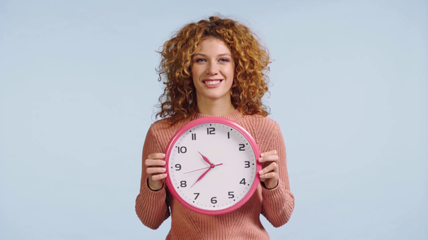 woman sticking out tongue and hiding behind clock isolated on grey - Footage, Video