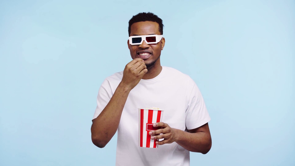 happy african american man watching movie isolated on blue - Кадри, відео