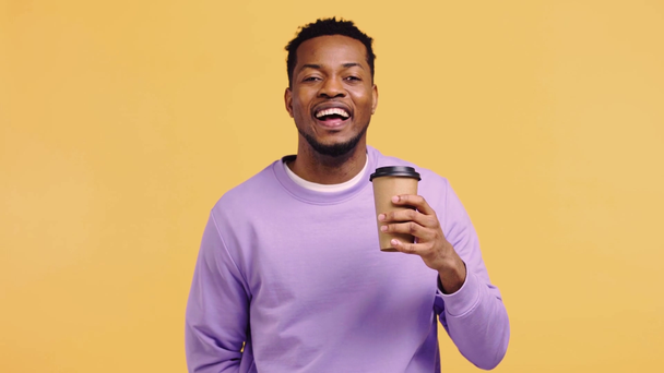Χαρούμενος Αφροαμερικάνος που πίνει καφέ απομονωμένος στο κίτρινο - Πλάνα, βίντεο