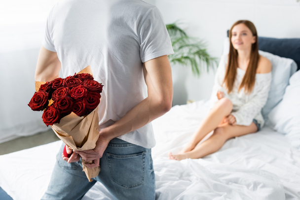 cropped view of man with bouquet and box and smiling woman looking at him  - Foto, afbeelding