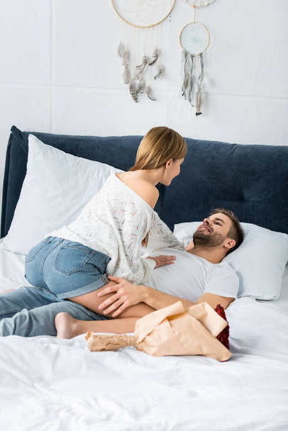 woman sitting on smiling and handsome man in bed  - Photo, image
