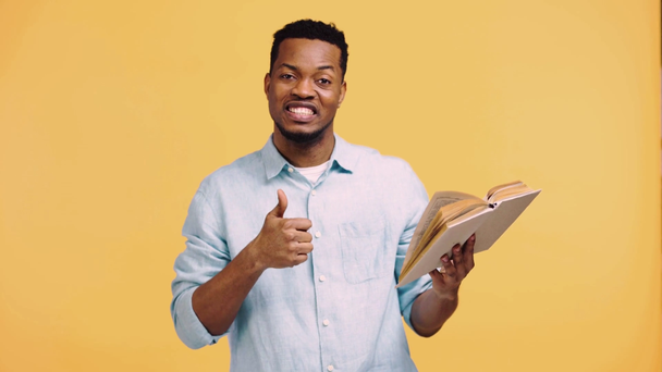 позитивний афроамериканський чоловік читає книгу ізольовано на жовтому
 - Кадри, відео