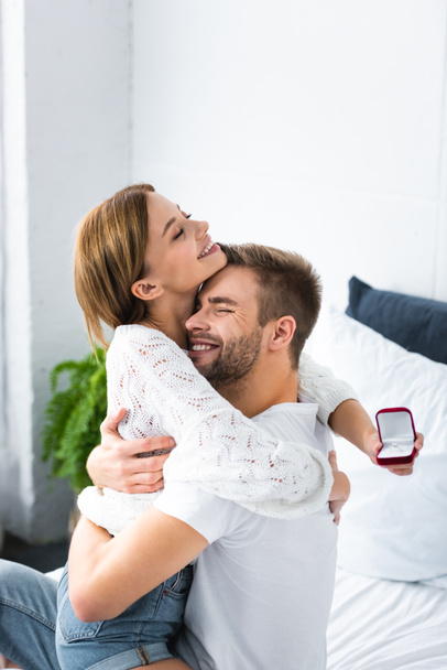handsome man hugging smiling woman with engagement ring - Fotografie, Obrázek