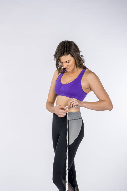 Gorąca brunetka fitness model Pomiar jej talii na białym tle  - Zdjęcie, obraz