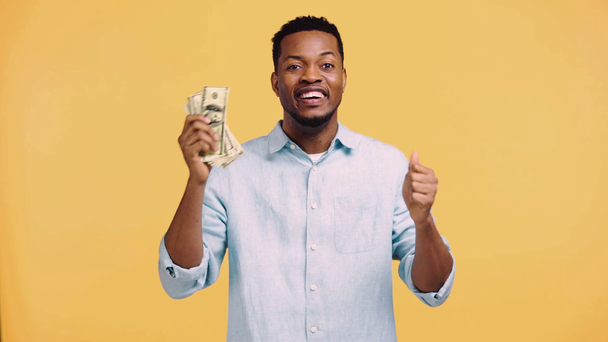 幸せなアフリカ系アメリカ人男性黄色で隔離されたお金を数える - 映像、動画