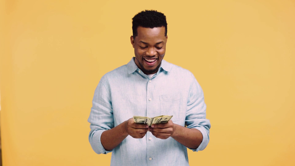 幸せなアフリカ系アメリカ人男性黄色で隔離されたお金を数える - 映像、動画